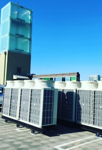 Cooling units in front of a modern glass tower